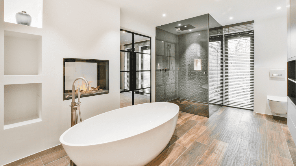 Luxury bathroom renovation: A sophisticated space with a marble bathtub, glass shower doors, and exquisite wood flooring as part of a premium property improvement service.